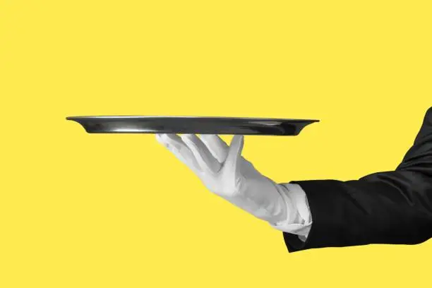 Elegant waiter hand in white glove holding an empty plate with  blank gradient background.