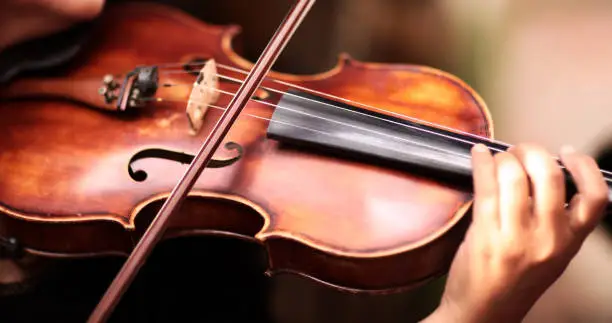 Photo of A person playing the violin showing hands holding the bow