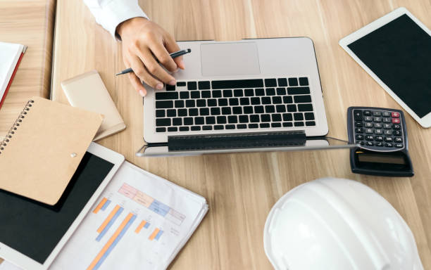 istock businessman using laptop computer accessories office equipment with tablet, calculator, mobile phone,note, pen, graph, safety helmet 849253502