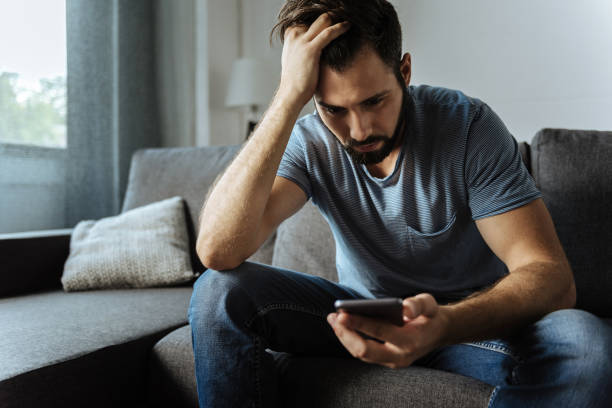 istock Cheerless handsome man looking at his smartphone screen 849253560