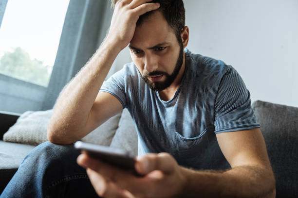 istock Cheerless gloomy man holding his smartphone 849253794