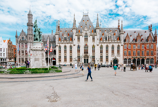 People on the Market square in Bruges. The Province Court (Provinciaal Hof) on the background