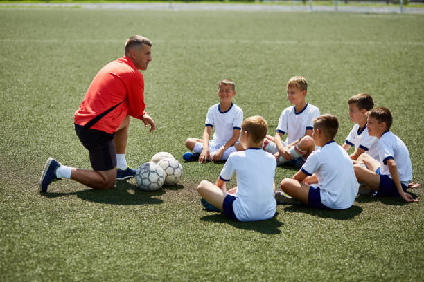 coach instructing junior football team - youth league fotos imagens e fotografias de stock