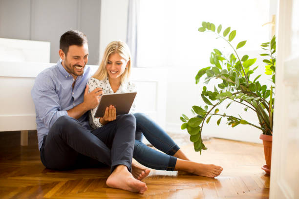 istock Young couple sitting on the floor with tablet 849259264