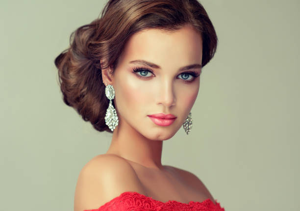 Gorgeous in a elegant make up and big fashionable jewelry earings. Young, gorgeous model is put on in a delicate make up, dressed in a red gown and big fashionable jewelry earings. Misty, romantic look. Wedding and evening style. bridal hair stock pictures, royalty-free photos & images