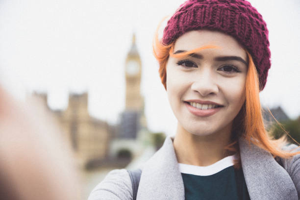 Smiling for a selfie to post on social media Taking a selfie on Westminster Bridge, with a defocused Big Ben in the background. big ben stock pictures, royalty-free photos & images