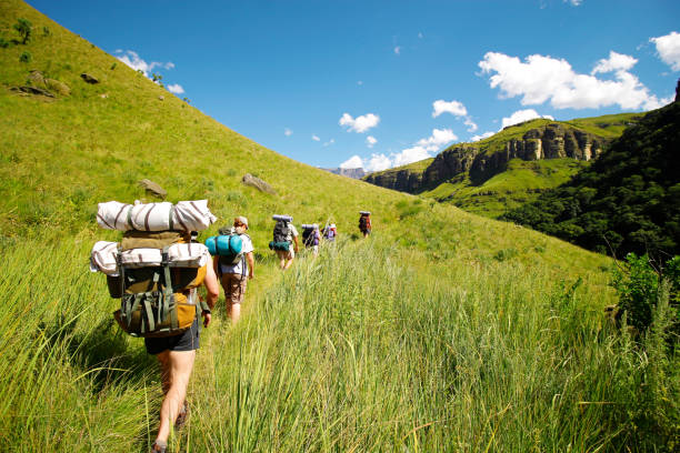 People hiking mountains rucksack boots camping Drakensberg grass hills sky stock photo