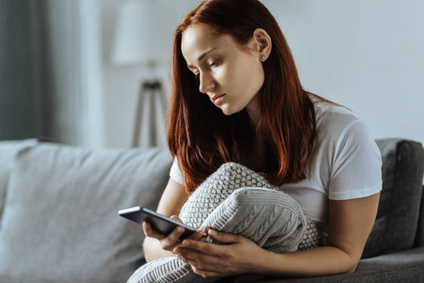istock Sad young woman holding her smartphone 849274078