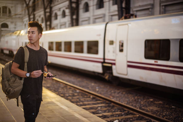 One man, standing on the subway platform, waiting for his train, using mobile phone.