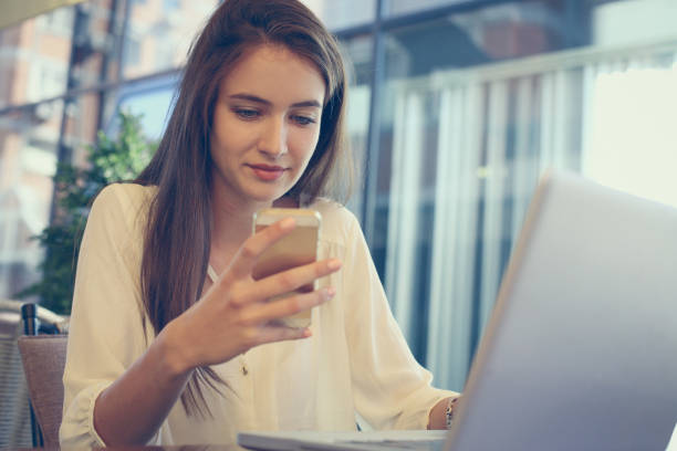 istock Businesswoman using laptop and texting with cell phone in office. 849279190