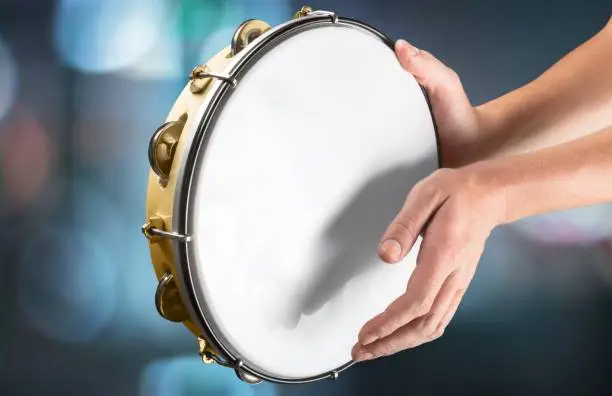 Female hands Playing the tambourine on background