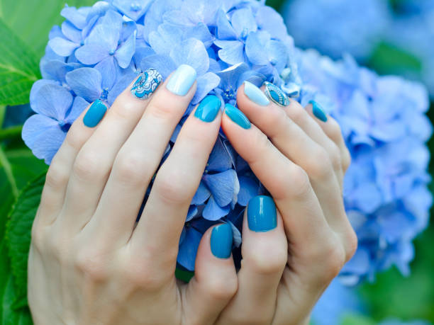 istock Female hands with a nice manicure on a blue flower 849282280