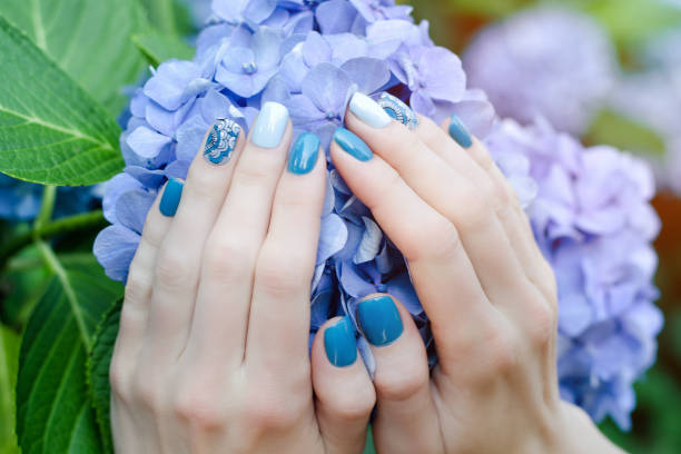 istock Female hands with a nice manicure on a blue flower 849283170