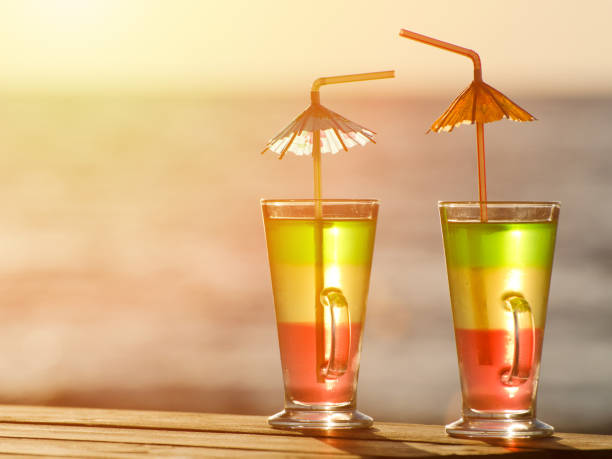 due cocktail colorati al tramonto sullo sfondo del mare, da vicino - umbrella two objects cocktail drink foto e immagini stock