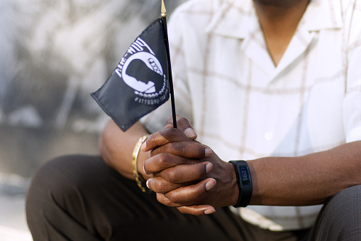 Philadelphia, PA, USA - September 15, 2017: An African-American man holds a black POW/MIA flag during an observance on National POW/MIA Recognition Day, at the Philadelphia Vietnam Veterans Memorial in Philadelphia, Pennsylvania.
