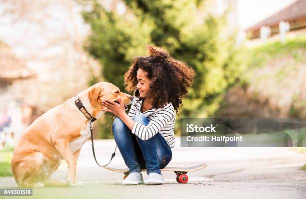 African American Girl Outdoors On Skateboard With Her Dog Stock Photo - Download Image Now