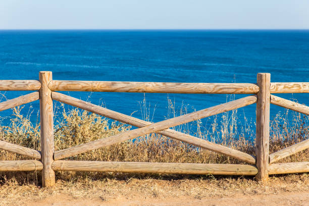 silhouette wooden fence with wavy blue sea behind