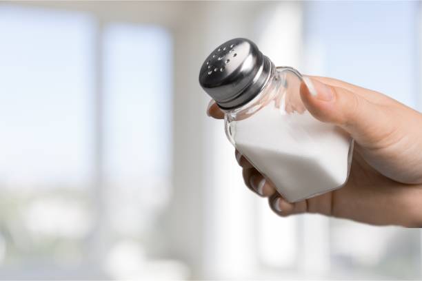 Salt shaker. Close up of hand holding white salt cellar salt seasoning stock pictures, royalty-free photos & images