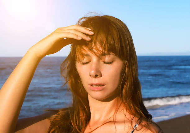 Young woman with heatstroke. Health problem on vacation. Medicine on vacation. Dangerous sun. Beach life. Sunstroke on hot beach. Girl under sun. Red hair girl on beach by sea. Holiday health care