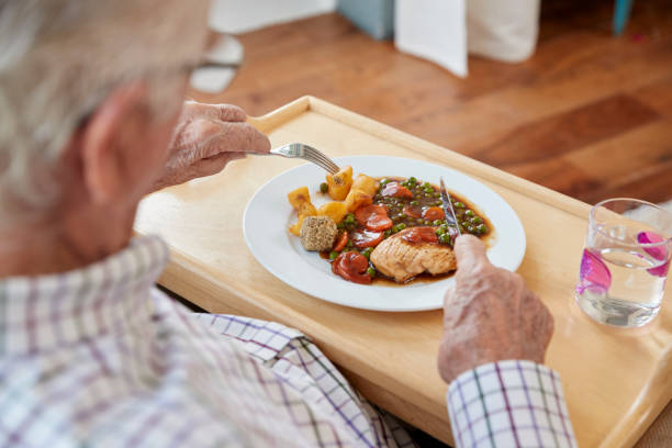 over shoulder view of senior man eating dinner at home - eating eat silverware horizontal imagens e fotografias de stock