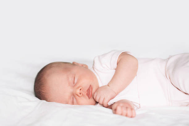 istock Sleeping newborn baby in a bodysuit on white blanket background. 849306138