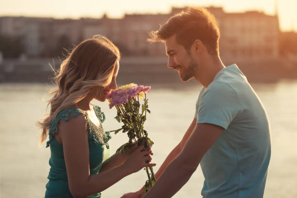 Man giving flowers to his girlfriend stock photo