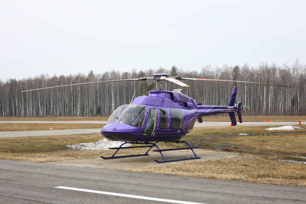 Aircraft - Purple helicopter on the parking against the wood and sky.