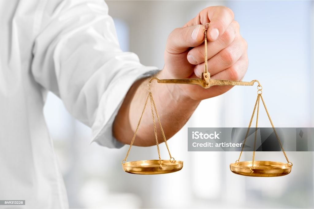 Balance. Hand holds scales symbol of justice against blue background Morality Stock Photo