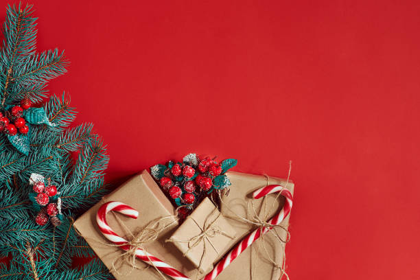 istock Christmas composition of pine cones, spruce branches and stack of gift boxes on red background 849317590