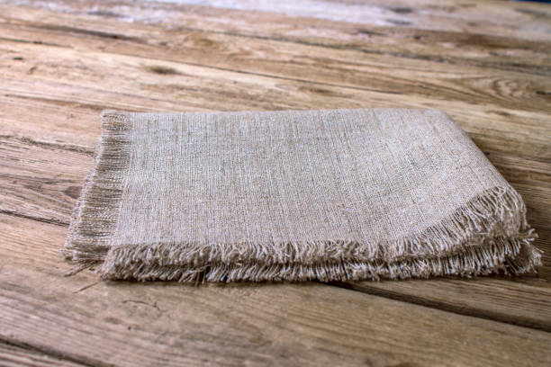 Folded linen napkin on old wooden kitchen table. stock photo