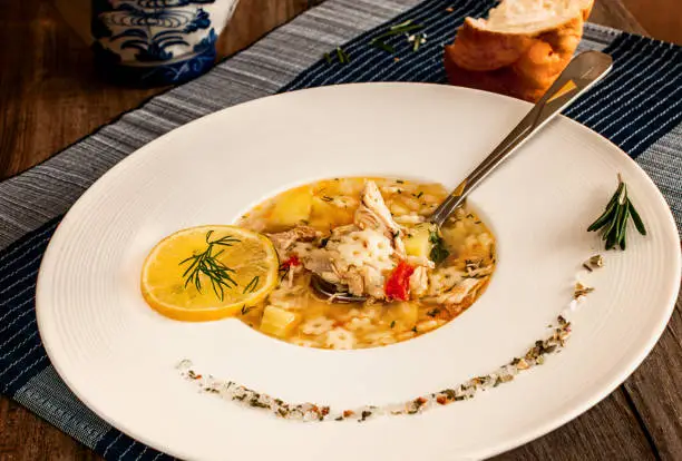 chicken soup in a white plate with pasta, lemon and spices