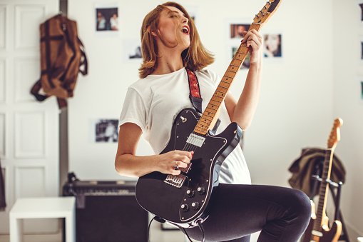 Young woman playing guitar in livingroom