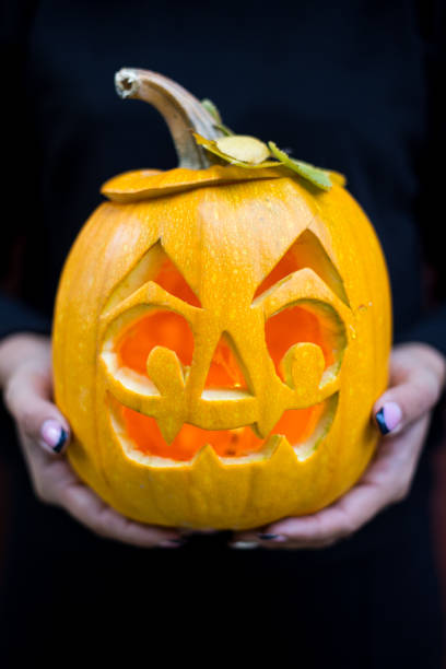 istock Halloween. Homan hands holding pumpkin on dark background 849332734