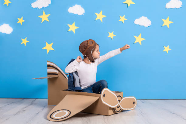 bambina in costume da pilota sta giocando e sognando di volare sopra le nuvole - stage costume immagine foto e immagini stock
