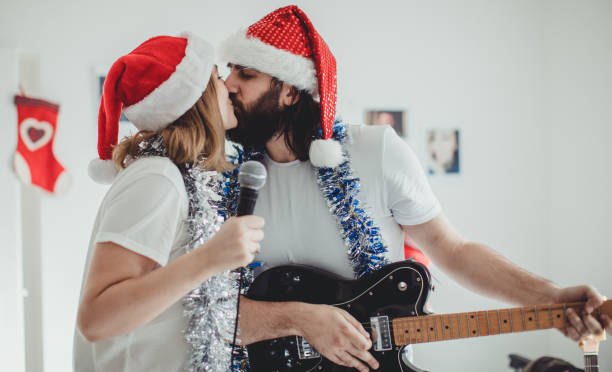 Time for christmas kiss Two people, young heterosexual couple, man playing guitar they are kissing, in home studio on christmas day.
 kiss entertainment group stock pictures, royalty-free photos & images