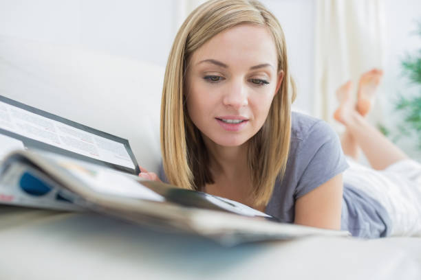 istock Casual woman reading magazine while lying on couch 849360902