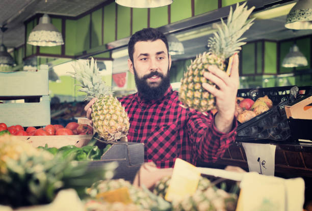 istock Young male seller offering pineapples 849384860