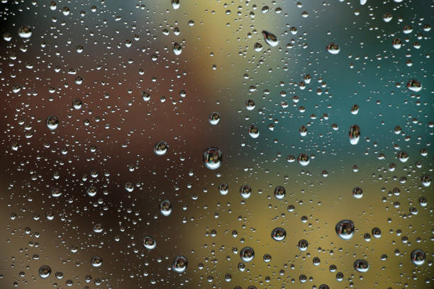 капли дождя на оконном стекле с красочным фоном - cold rain parasol gray стоковые фото и изображения