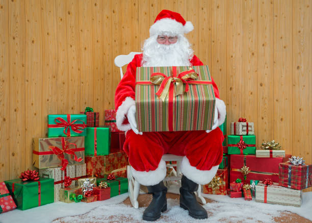 Santa Claus in his grotto holding a gift wrapped present