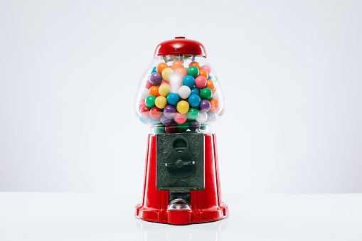 A classic red bubble gum ball vending machine.  Shot on white studio background.