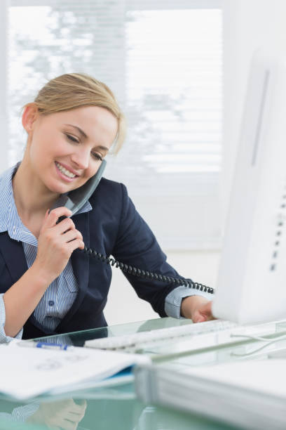 istock Female executive using landline phone and computer at desk 849406624