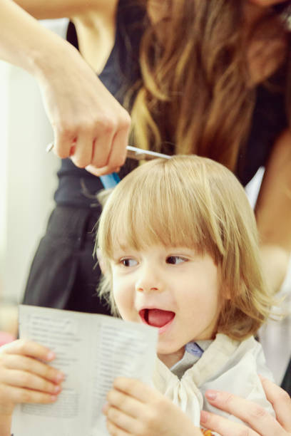 Happy child at the hairdresser Male child gets his first haircut körperpflege stock pictures, royalty-free photos & images