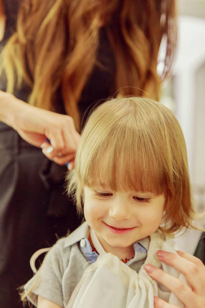 Happy child at the hairdresser Male child gets his first haircut körperpflege stock pictures, royalty-free photos & images