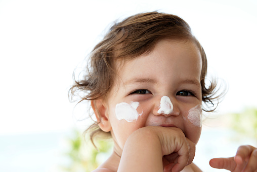 Smiling baby with suncream in face