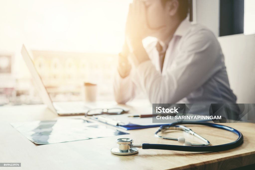 Stethoscope and doctor sitting with laptop  stress headache about work in hospital Doctor Stock Photo