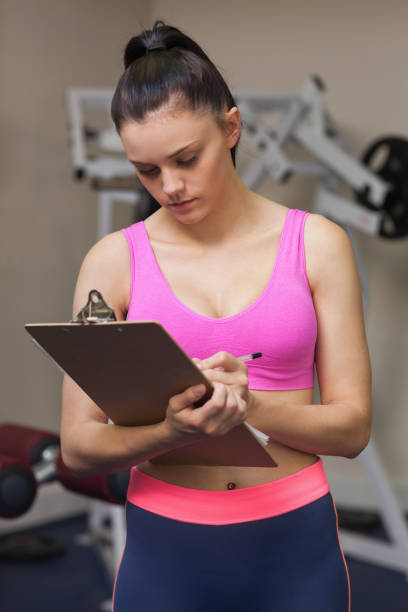 istock Serious female trainer with clipboard in gym 849436718