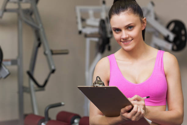 istock Smiling female trainer writing on clipboard in gym 849436818