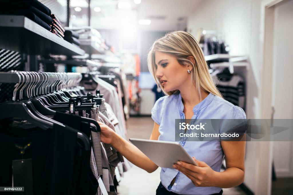 It's time to shop Young woman using digital tablet while shopping in the clothing store. Digital Tablet Stock Photo