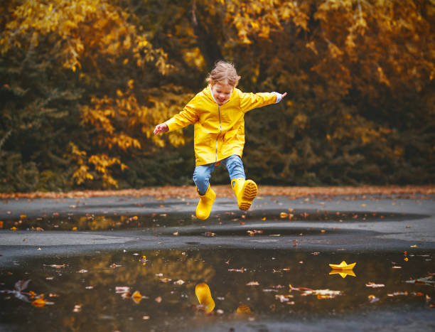 happy child girl with an umbrella and rubber boots in puddle  on autumn walk - puddle imagens e fotografias de stock