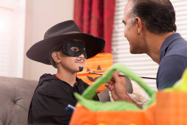 istock Little boy dresses up for Halloween with dad's help. 849466328